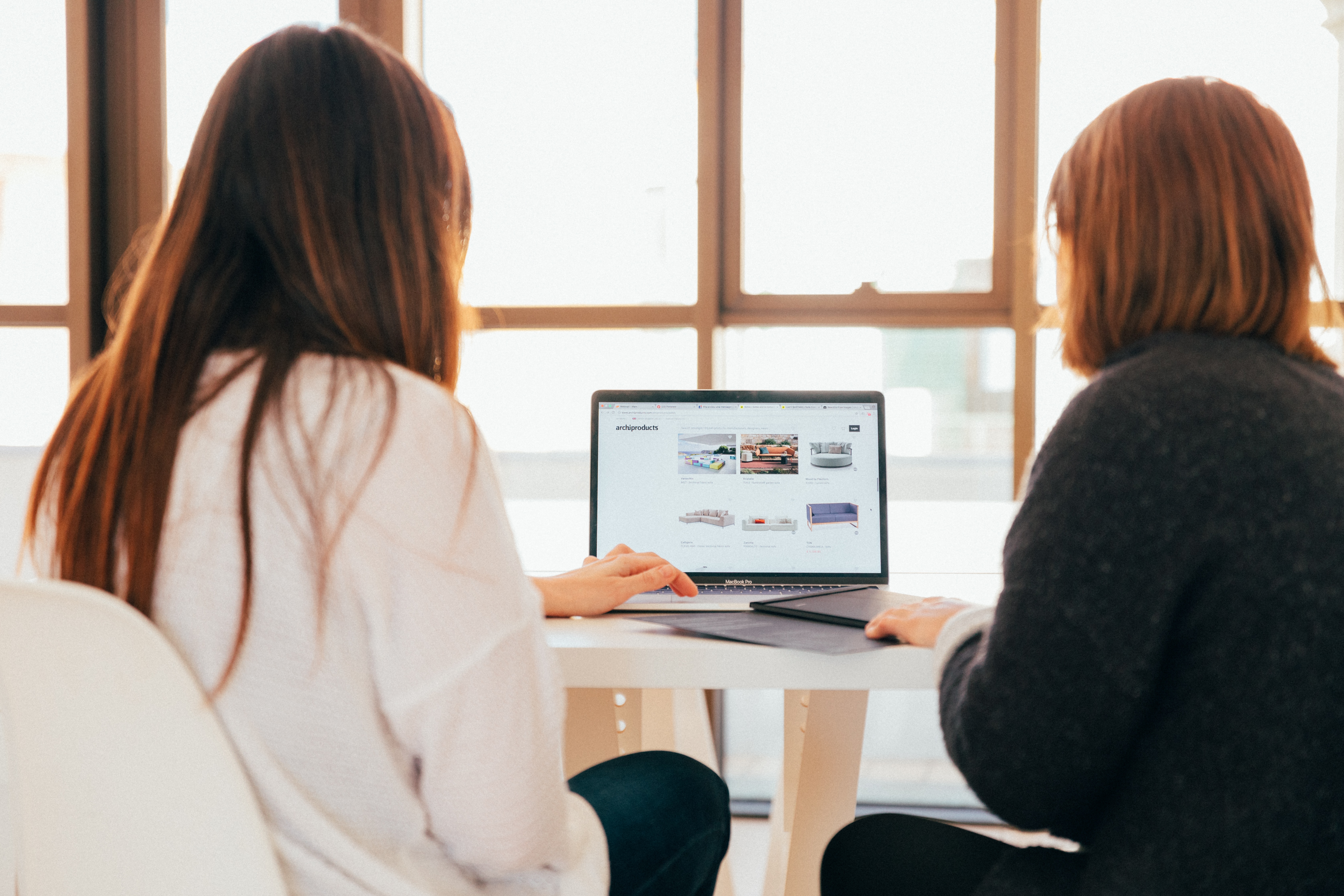 Two women looking at a computer showing ads